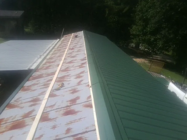 Old rusted panels beside newly installed green metal roofing — Wind Damage Roof Repair by Roofing Brothers in Huntington Park