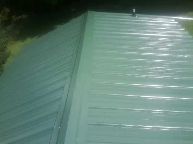 New green metal panels meeting at the ridge of a roof — Flat Roof Repair work by our crew in Huntington Park