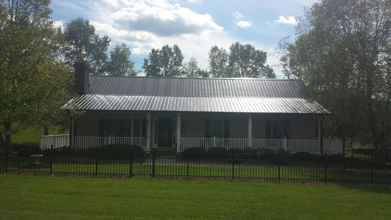 Gray metal roof on a brick ranch with a full width front porch — Gutter Guard Installation work by our crew in Huntington Park