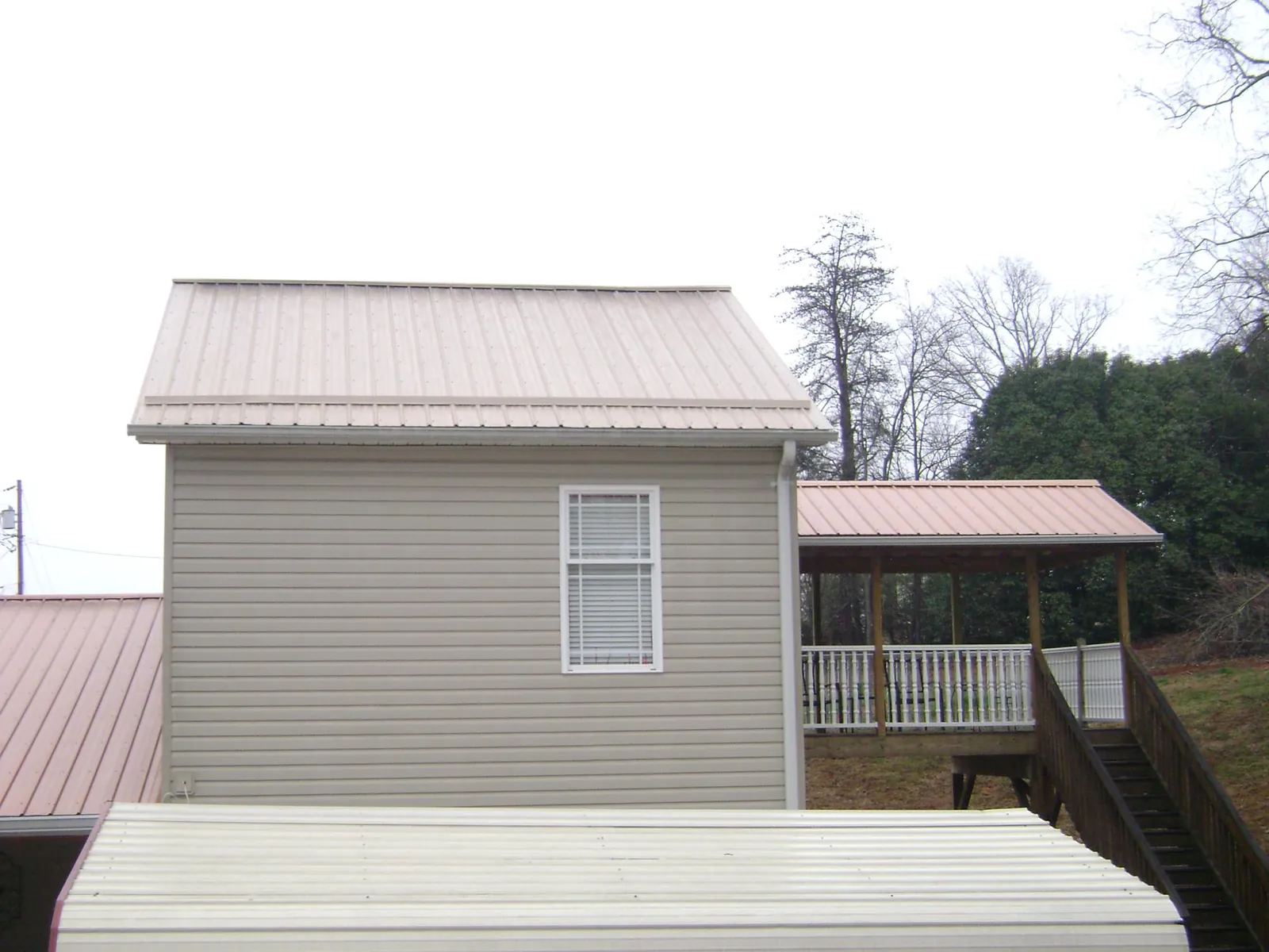 Tan metal roofs on a two story addition and attached porch, from a Roof Replacement job in Huntington Park