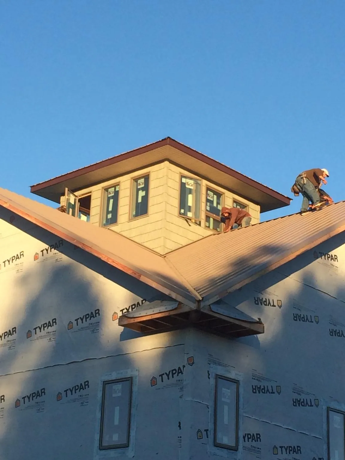 Roofers working around a rooftop cupola on a new metal roof at sunset — Roof Waterproofing in Huntington Park by Roofing Brothers